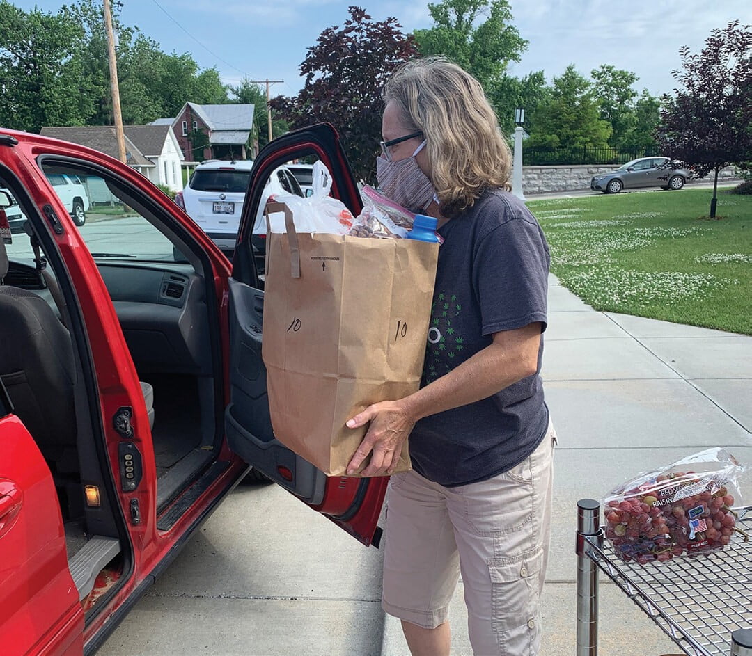 A food pantry volunteer loading a bag of groceries into a car