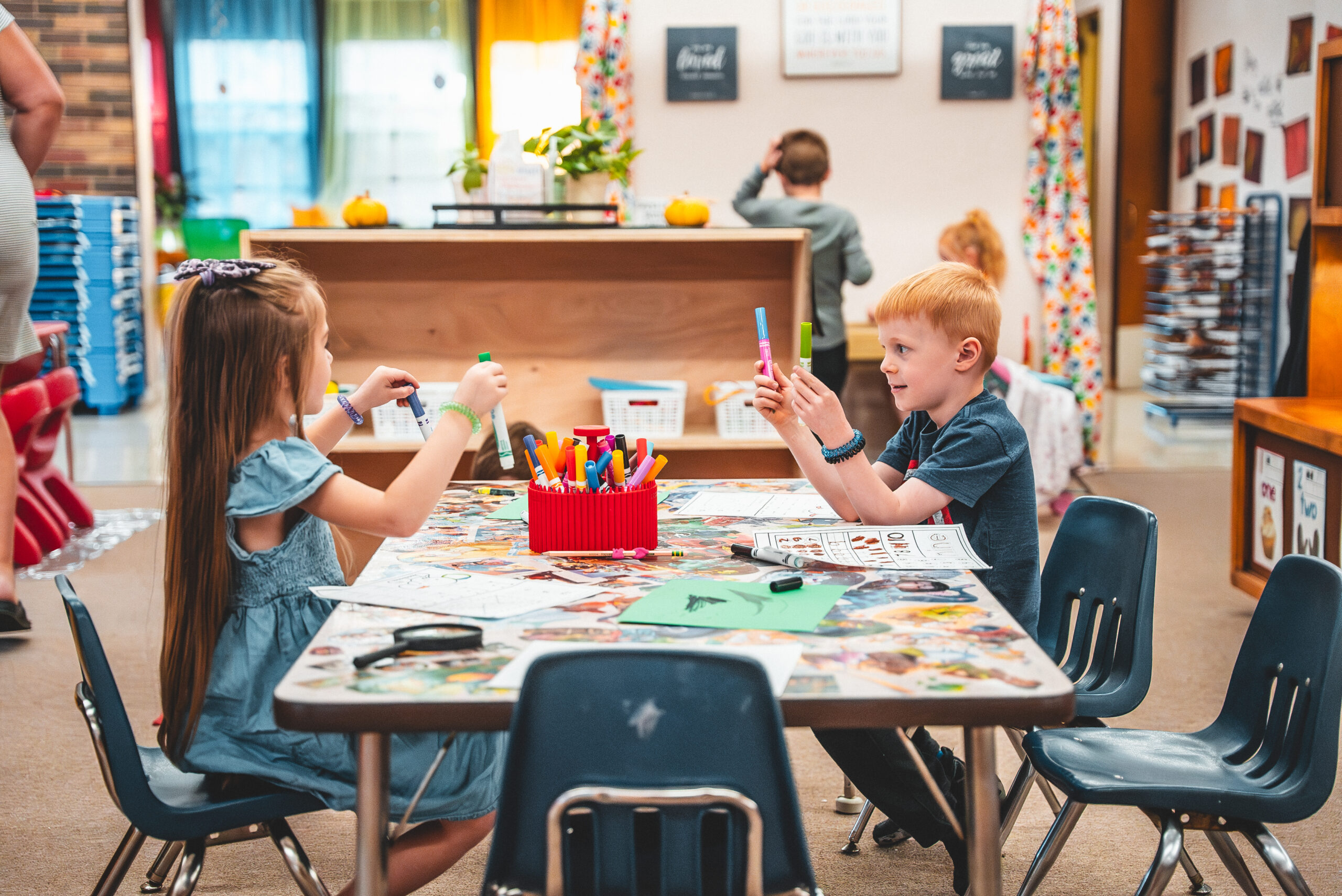 Preschoolers drawing with markers at a classroom table