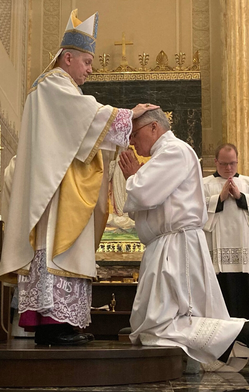 The bishop laying hands on a kneeling candidate during an ordination Mass