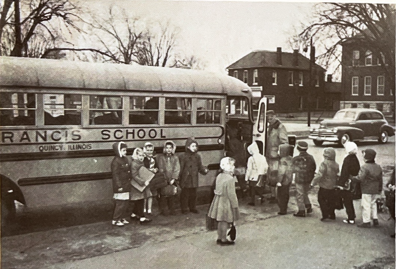 Children in winter coats lining up to board the St. Francis School bus in Quincy, mid-1900s