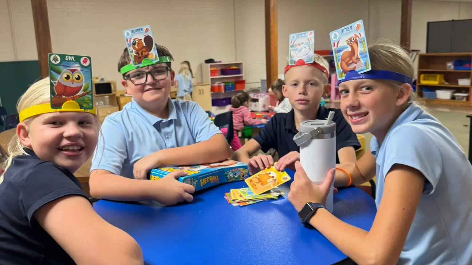 St. Francis students laughing while playing a card game with picture cards on their headbands