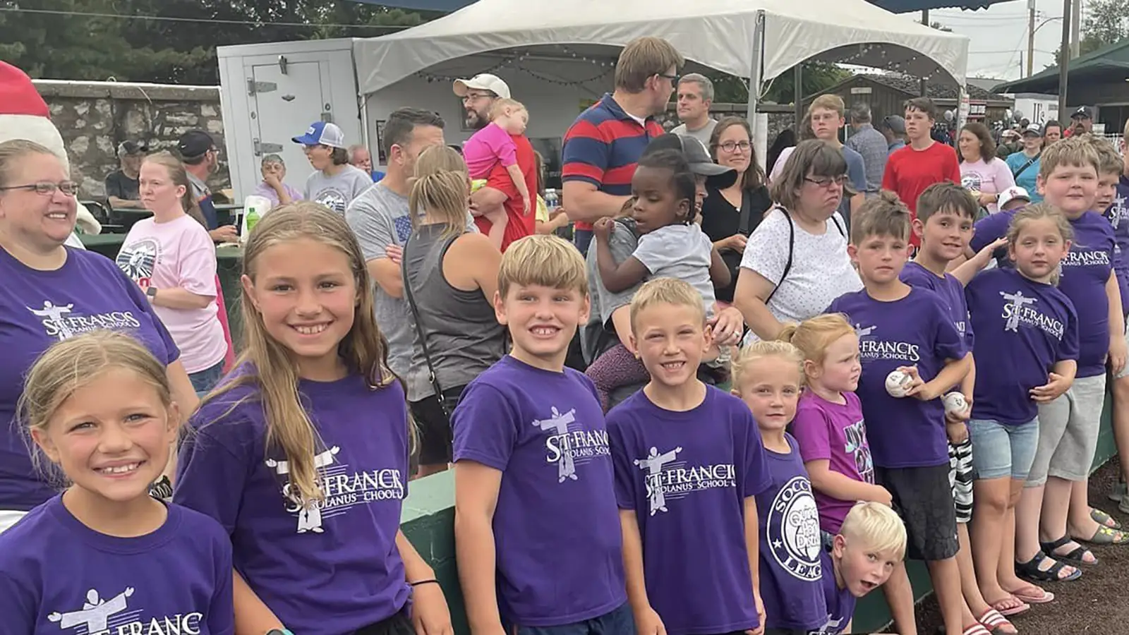 St. Francis families in purple school shirts gathered together at an outdoor event