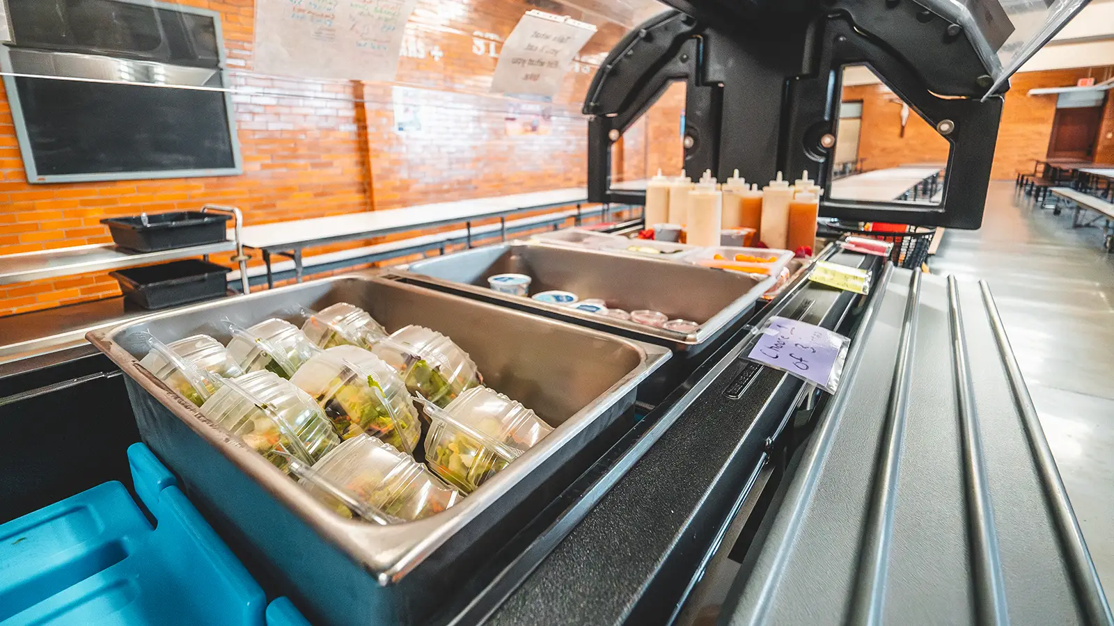 The cafeteria salad bar stocked with packaged salads and dressings