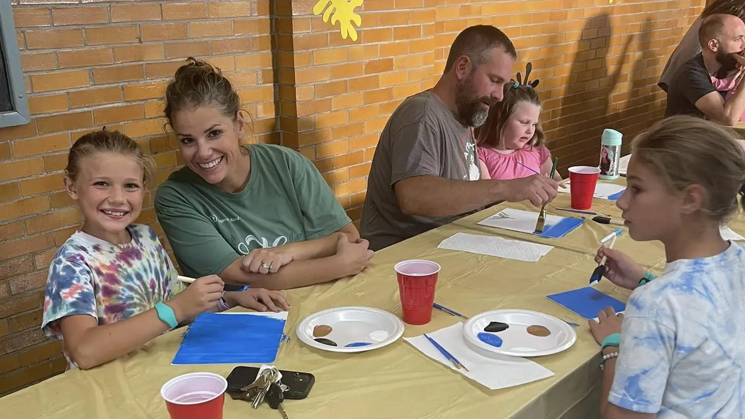 A St. Francis mom and her daughters painting together at a PTO family paint night