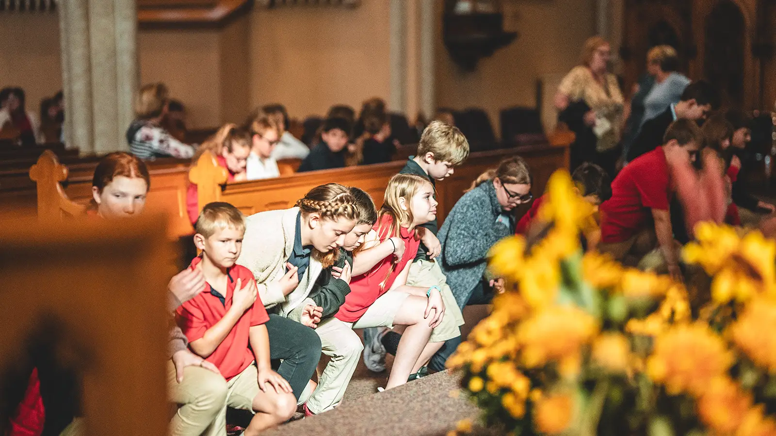 Young St. Francis students praying together in the church pews