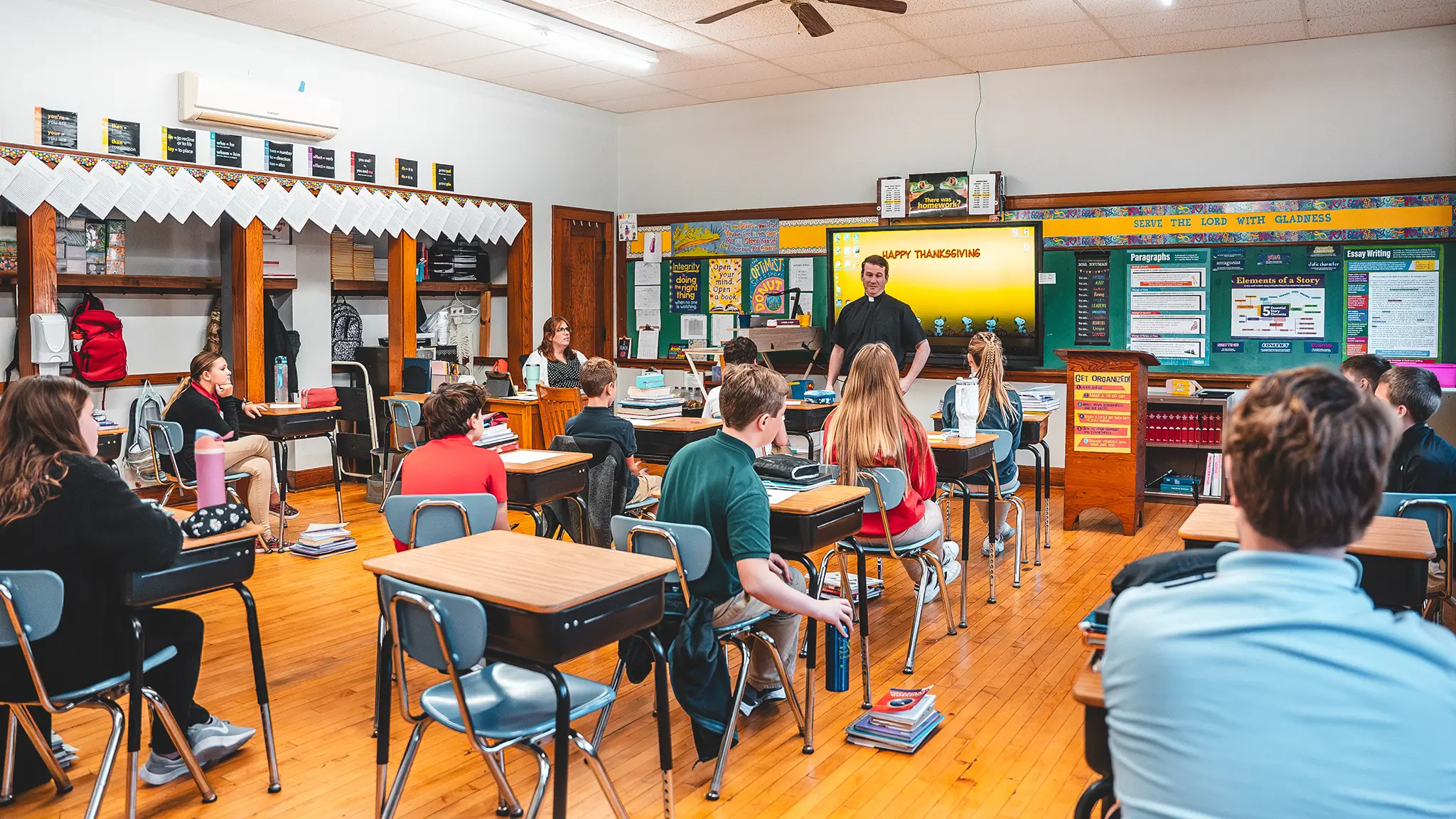 A priest teaching at the front of a St. Francis classroom