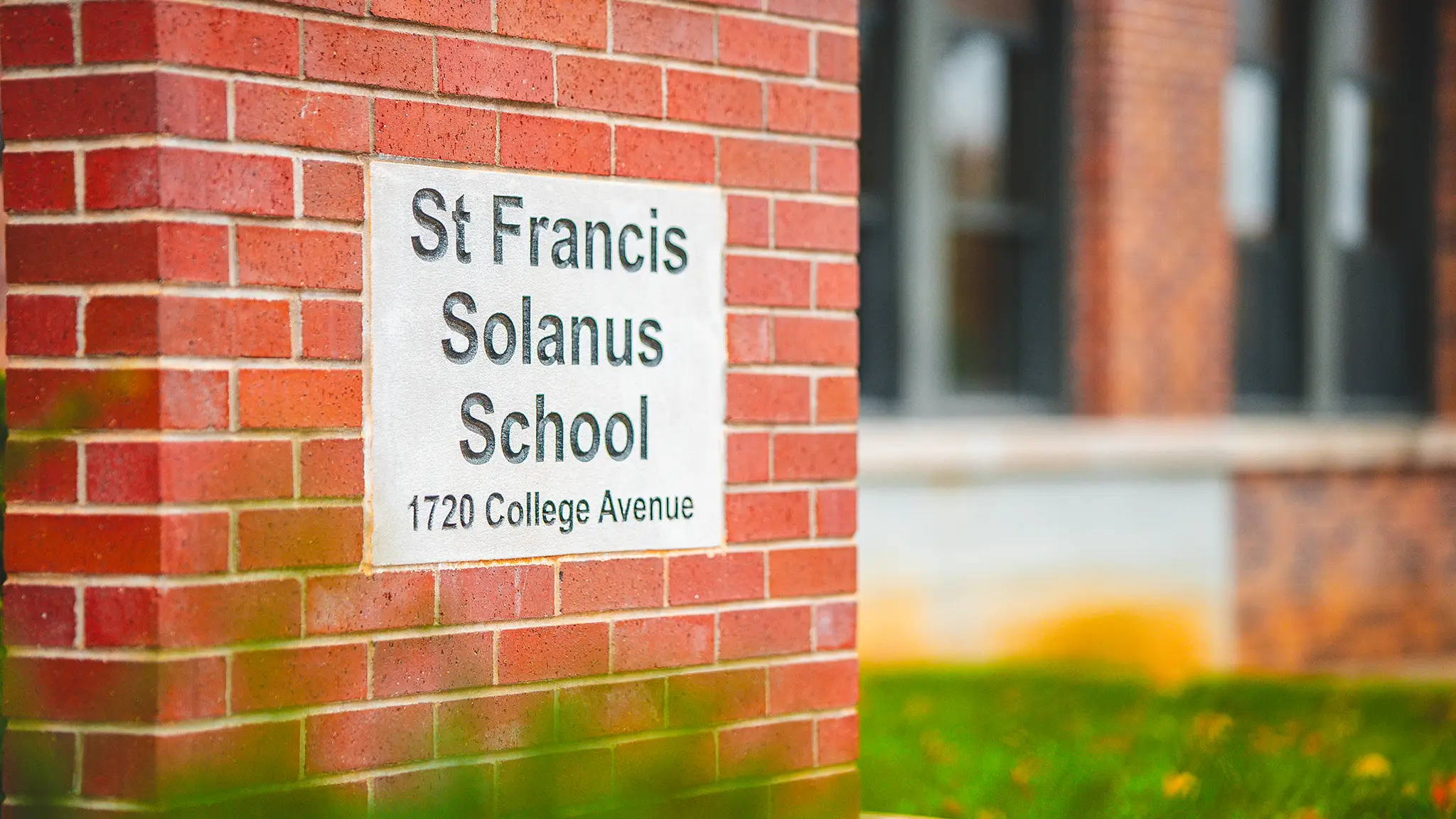 The St. Francis Solanus School sign set into the brick wall at 1720 College Avenue