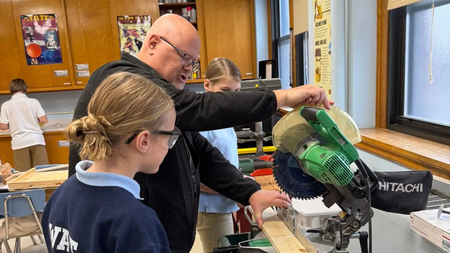 Mr. Carey showing St. Francis students how to use a mitre saw in the STREAM lab