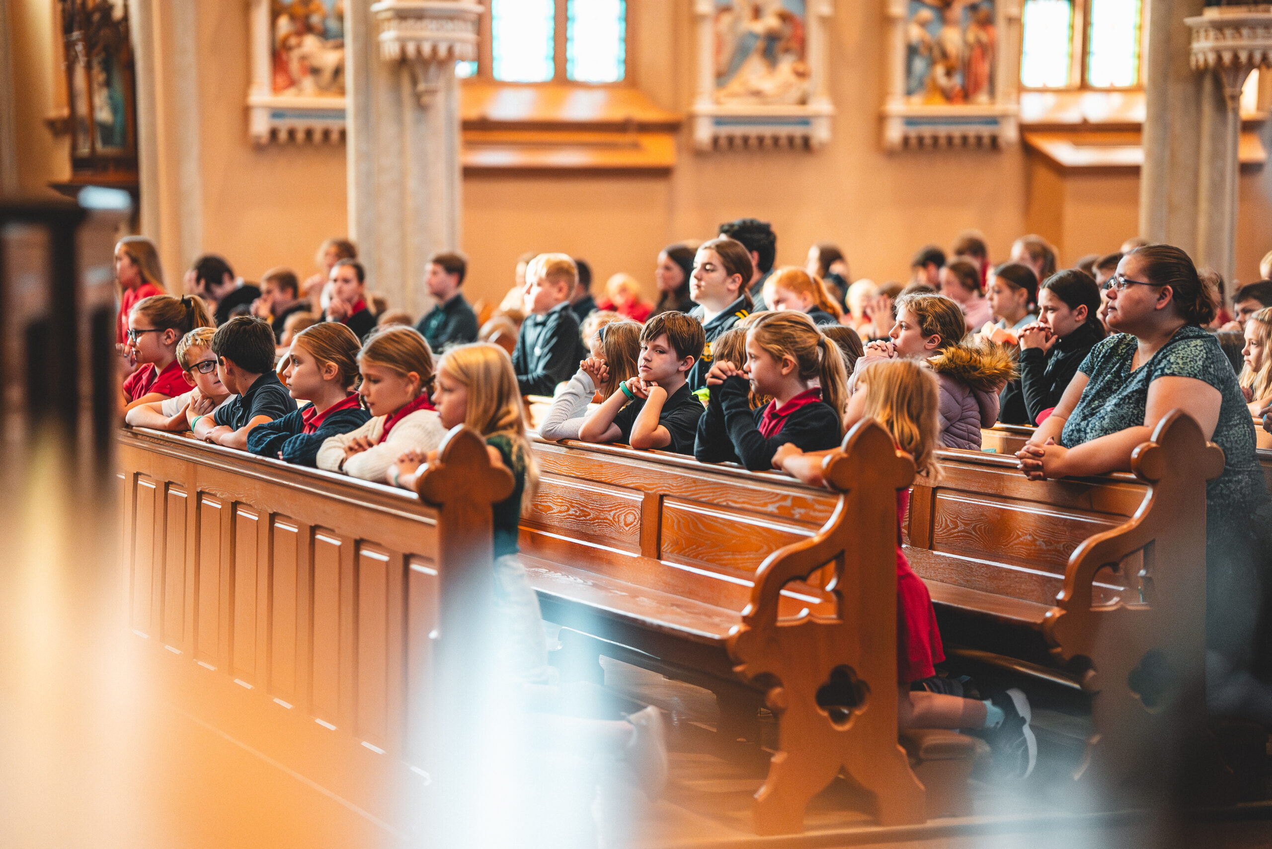 St. Francis students and a teacher seated in the church pews during an all-school Mass
