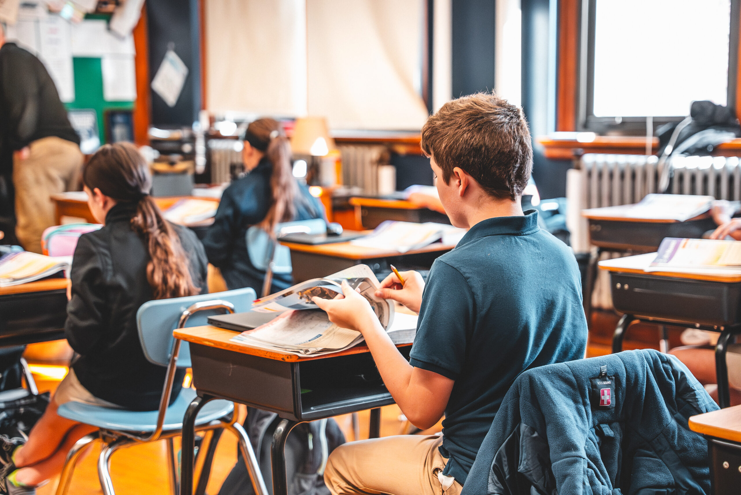 A St. Francis middle school student writing at his desk during class