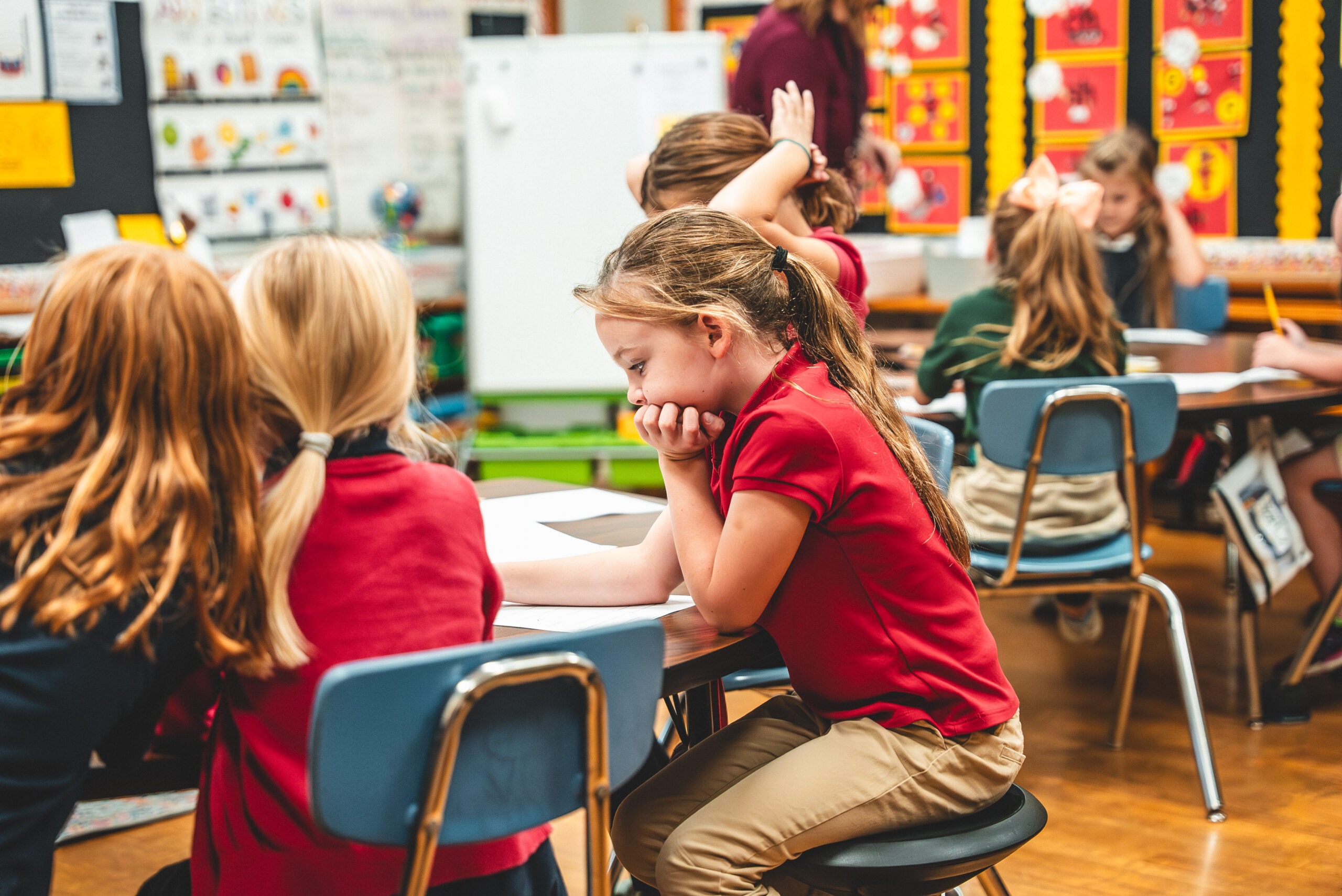 St. Francis students in red uniform shirts working together at a classroom table