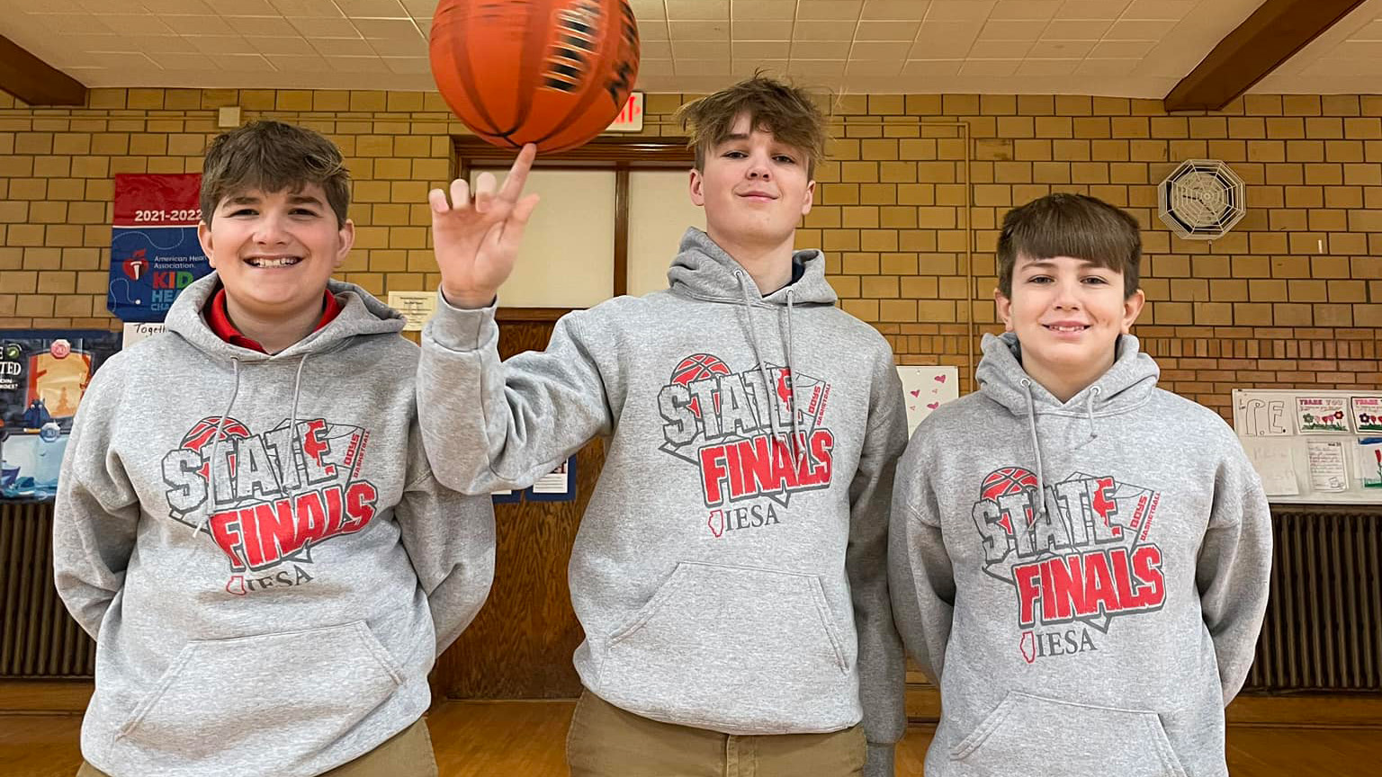Three St. Francis boys in IESA State Finals sweatshirts, one spinning a basketball on his finger