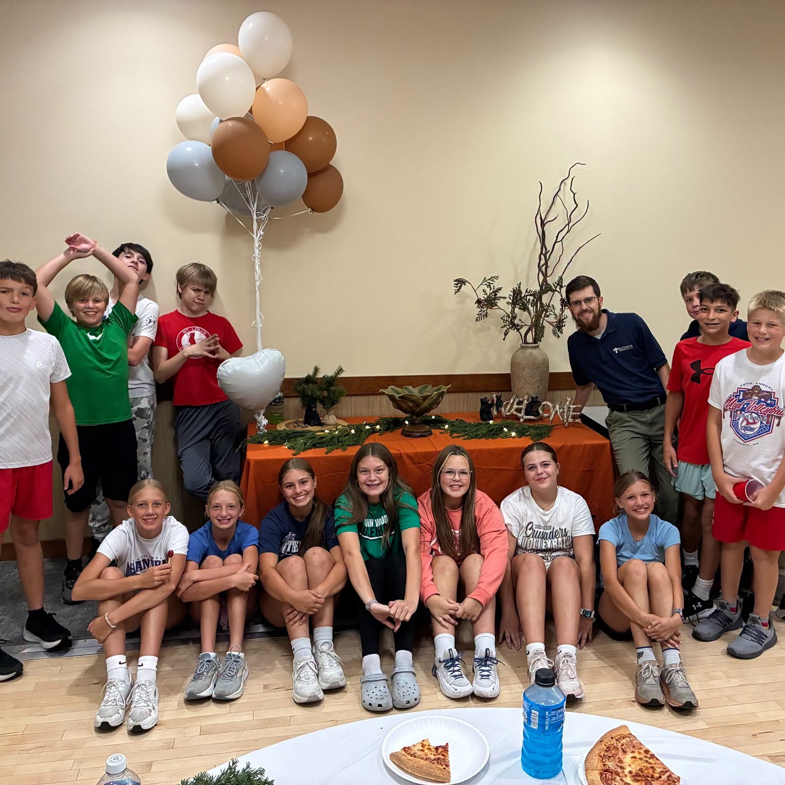 BEAR youth group students and their leader gathered together in the parish hall with balloons and pizza