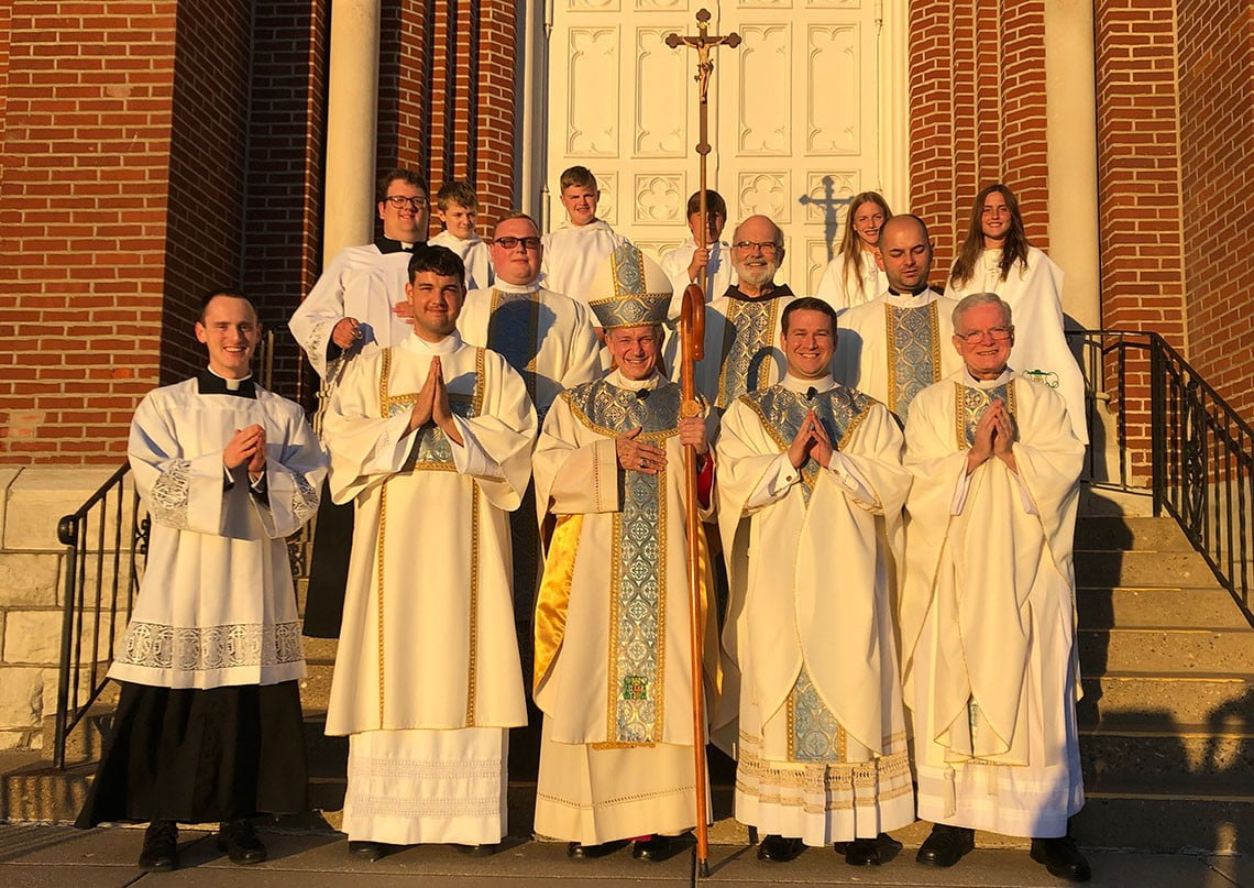 The bishop with priests, deacons, and altar servers on the steps of St. Francis Solanus Church
