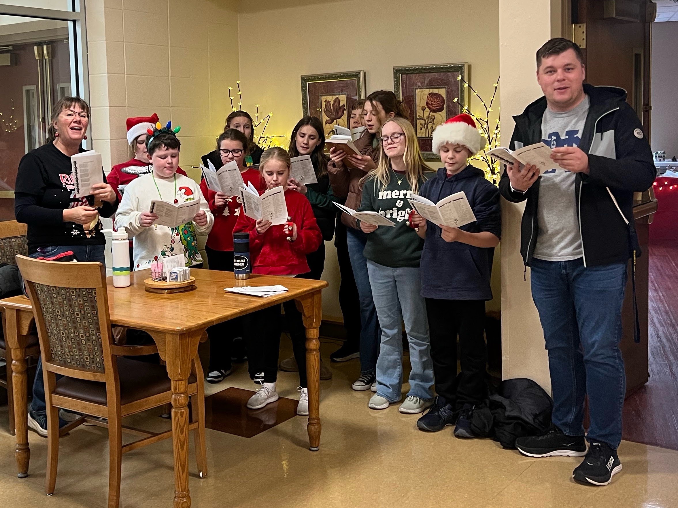 St. Francis students in Santa hats singing Christmas carols from song sheets